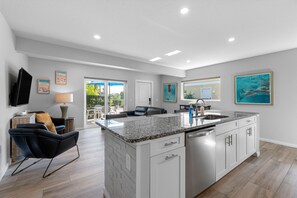 A modern kitchen with white cabinets, a granite countertop, and a built-in dishwasher.