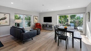 Una sala de estar moderna con un sofá, una mesa de comedor, sillas y un televisor.