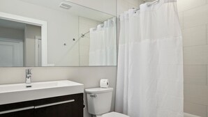 Une salle de bain moderne avec un lavabo blanc, des toilettes et un rideau de douche.