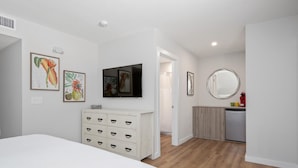Une chambre à coucher comprenant un lit, une commode et des œuvres d’art accrochées au mur.