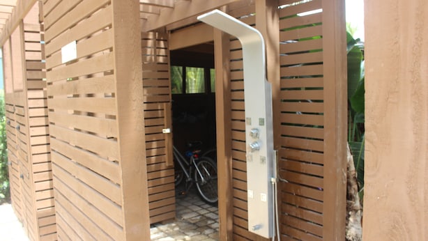 Une structure en bois comprenant un espace douche, avec un pommeau de douche et un panneau de commande.