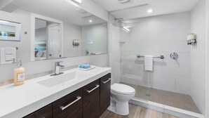 A modern bathroom with a large mirror, a sink, a toilet, and a shower area.