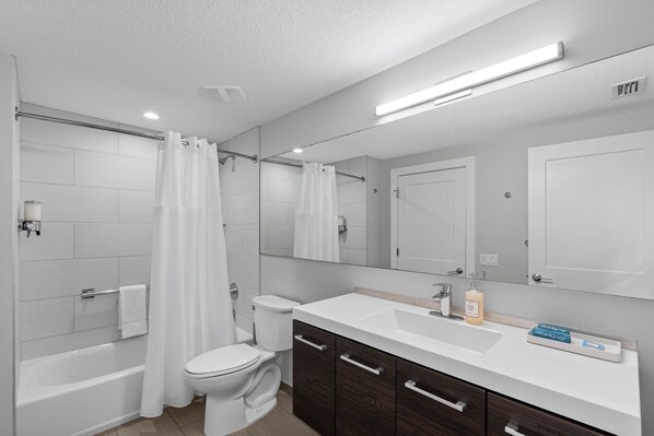 A modern bathroom with a bathtub, toilet, and vanity.