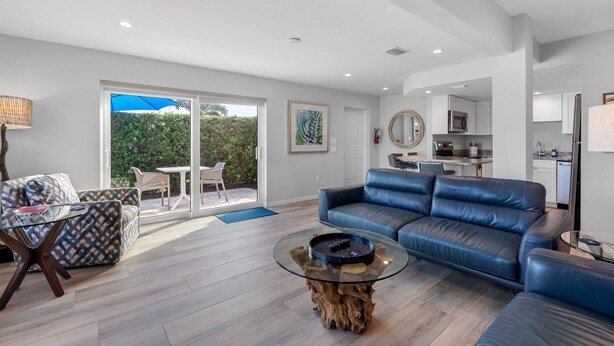 A modern living room with a leather sofa, a glass coffee table, and a dining area with a white table and chairs.