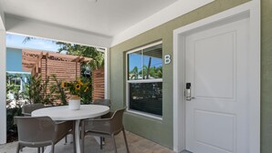 Une terrasse avec une table ronde et des chaises, une pergola en bois et une vue sur l’extérieur.