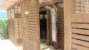 Une structure de pergola en bois dotée d’un espace douche, comprenant un pommeau de douche et un panneau de commande.
