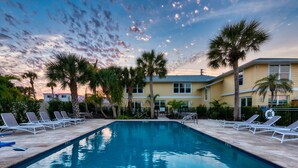 A swimming pool with lounge chairs, palm trees, and a building in the background. - Hotel Studio (Ground Level) - Unit C (Nokomis)