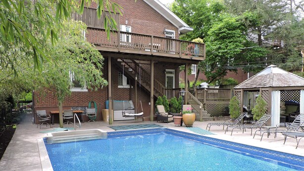 A backyard with a swimming pool, a wooden deck, and outdoor furniture. - Bright, Parkside condo with pool (Louisville)