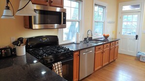 A kitchen with wooden cabinets, a stainless steel microwave, a gas stove, and a dishwasher. - Bright, Parkside condo with pool (Louisville)