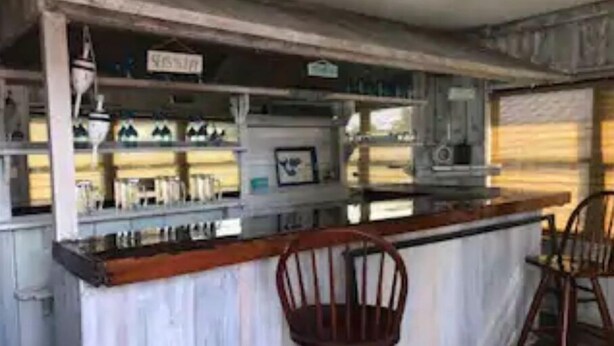 A rustic bar area with wooden shelves and stools. - The Mermaid Beach House 2 (Hernando Beach)
