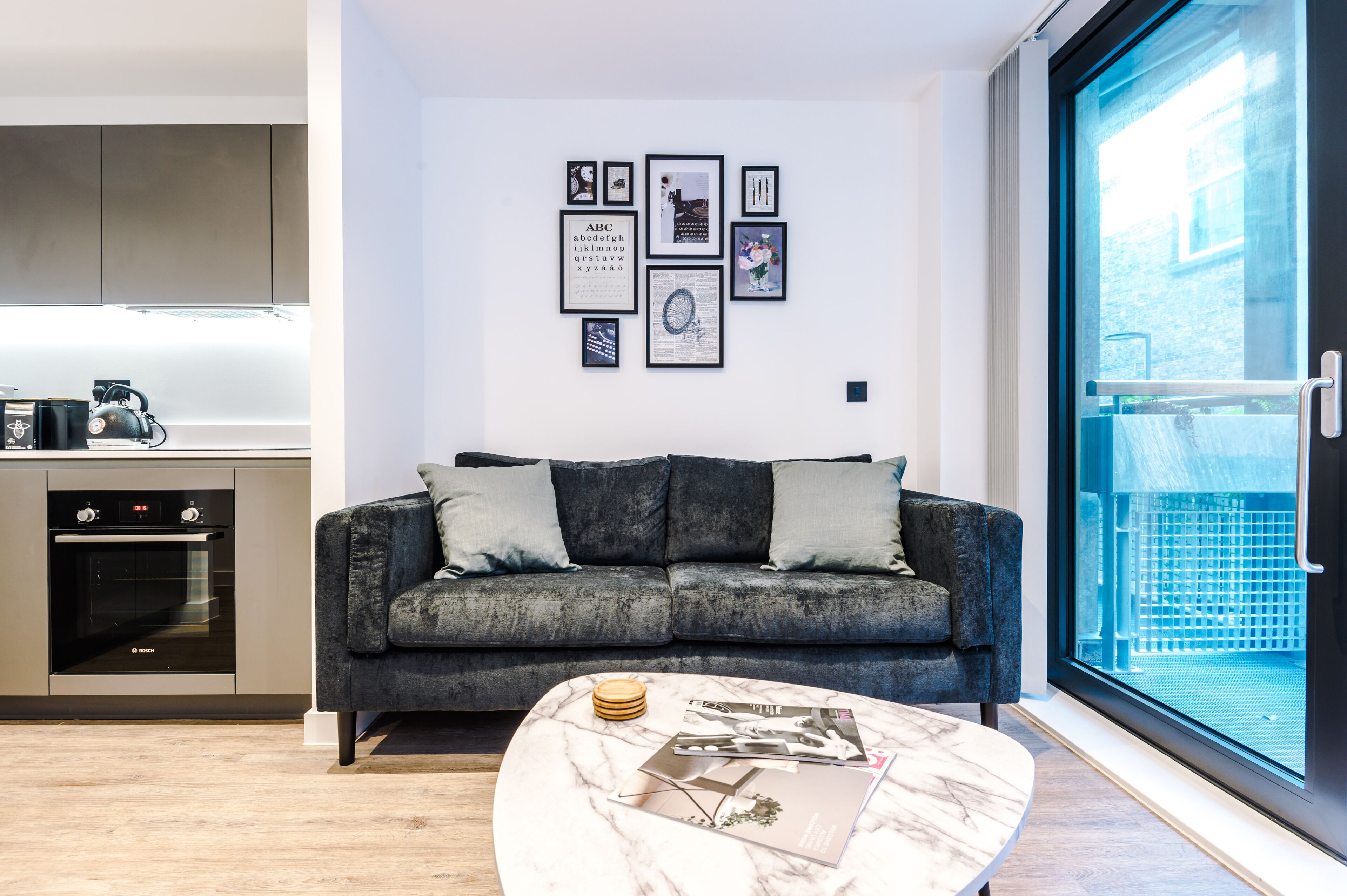 A modern living room with a grey sofa, a marble coffee table, and framed pictures on the wall.