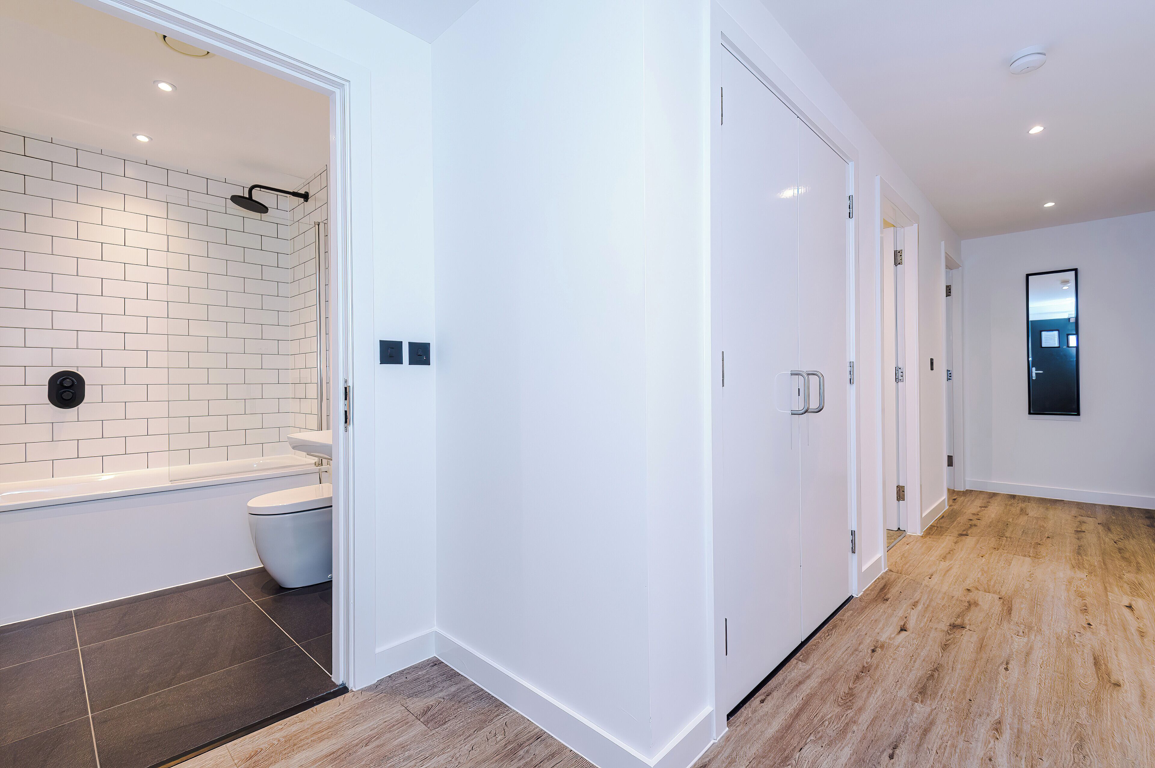 A modern bathroom with a white bathtub, a toilet, and a shower area.