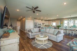 A spacious living area with a sectional sofa, a round coffee table, and a ceiling fan.