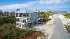 A multi-story building with balconies, a driveway, and a beach view.
