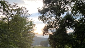 A glass of red wine on a wooden deck overlooking a lake with trees and a sunset in the background. - 10 Star River Front Retreat - Water Sports, Hiking, Campfires by the River (Sparta)