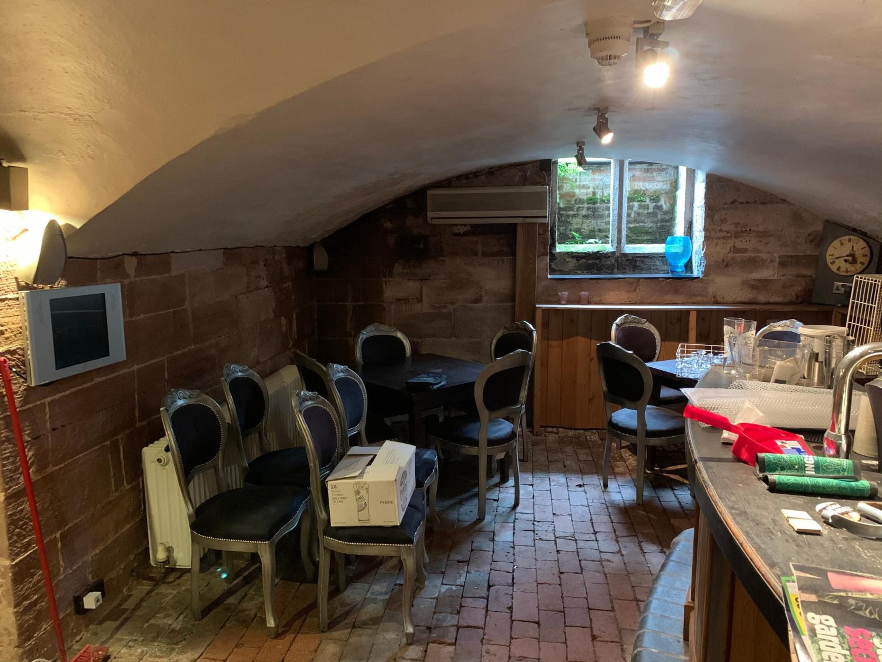 A dining area with a brick floor, a table with chairs, a window with a view, and a clock on the wall.