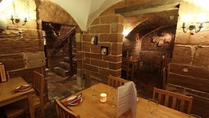 A restaurant with stone walls, wooden tables, and a staircase leading to an upper level. - The Silk House (Leek)