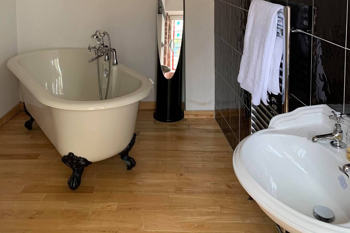 A bathroom with a freestanding bathtub, a sink, and a mirror.
