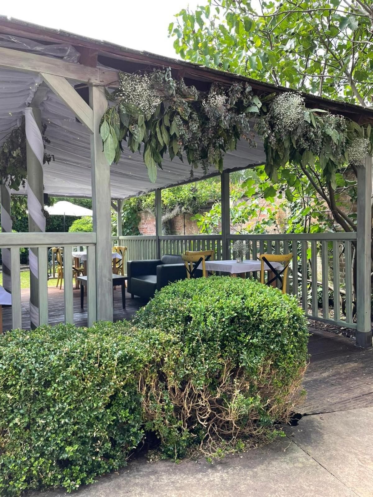 An outdoor patio with a covered seating area, tables, and chairs.