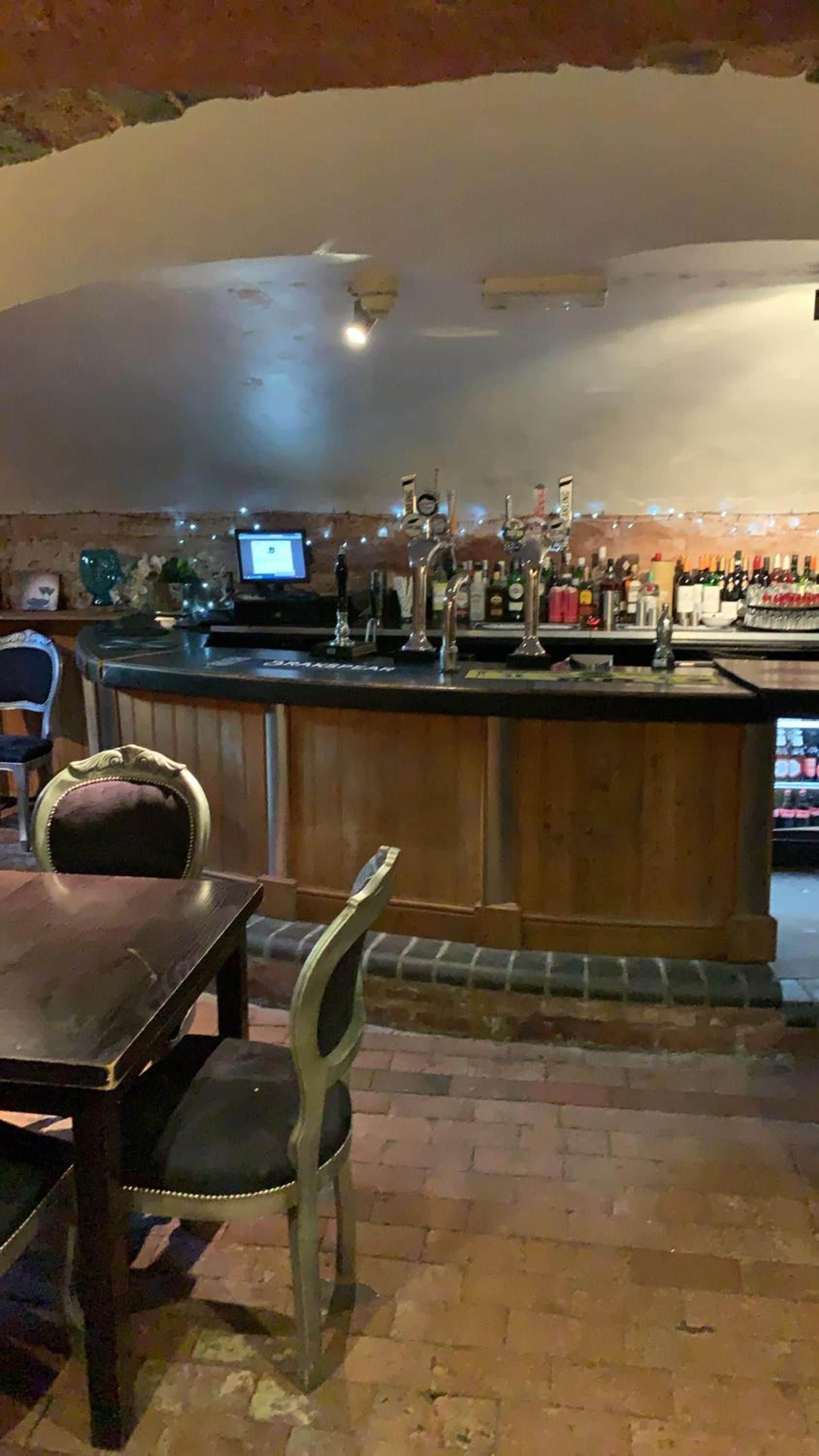 A bar area with a counter, bar stools, and a television screen.
