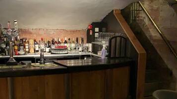 Zona de bar con mostrador, taburetes y una escalera que sube a un nivel superior.