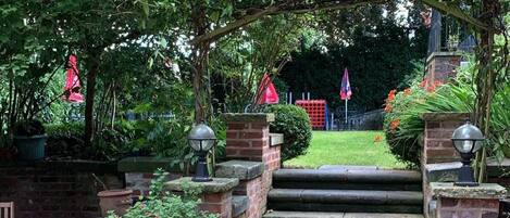 A stone staircase leading to a covered area with brick walls and potted plants.