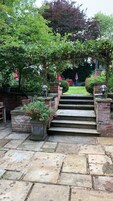 A stone staircase leading to a covered area with brick walls and potted plants.