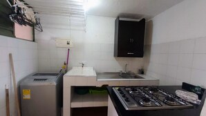 Una cocina compacta con estufa a gas, un lavamanos y un refrigerador pequeño.