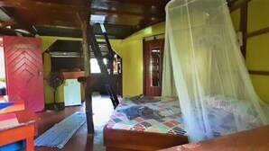 Een kamer met een bed dat is afgedekt met een klamboe, een houten vloer en een rode deur.