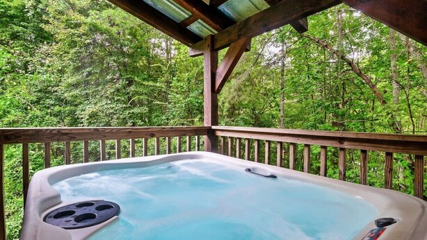 Ein Whirlpool auf einer Holzterrasse mit Wald im Hintergrund.