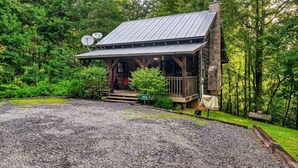 Eine rustikale Holzhütte mit einem Metall-Dach, einer Holzterrasse und Satellitenschüsseln.