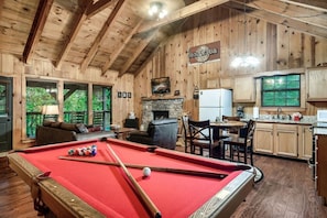 Ein Holzinterieur mit Billardtisch, Kamin und Küchenbereich.