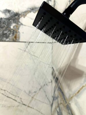 A showerhead with water flowing down a marble surface.