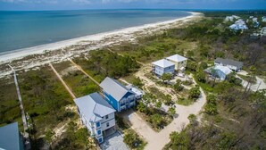 An aerial view of a coastal property with multiple buildings, a beach, and a clear sky. - Upscale Beach Front Home w/Elevator, Private Pool, Fire Pit! (Cape San Blas)
