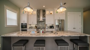 A modern kitchen with a large island, stainless steel appliances, and pendant lighting. - Upscale Beach Front Home w/Elevator, Private Pool, Fire Pit! (Cape San Blas)