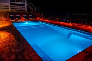 A rectangular swimming pool with a blue interior, surrounded by a brick patio and a metal fence. - Upscale Beach Front Home w/Elevator, Private Pool, Fire Pit! (Cape San Blas)