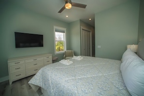 A bedroom with a bed, a dresser, a chair, a ceiling fan, and a window. - Upscale Beach Front Home w/Elevator, Private Pool, Fire Pit! (Cape San Blas)