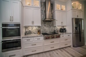 A modern kitchen with white cabinetry, a stainless steel range, and a built-in oven. - Upscale Beach Front Home w/Elevator, Private Pool, Fire Pit! (Cape San Blas)