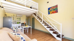 A modern living room with a staircase, a dining area, and a kitchen. - Ocean Winds Suite Hotel (Lowlands)
