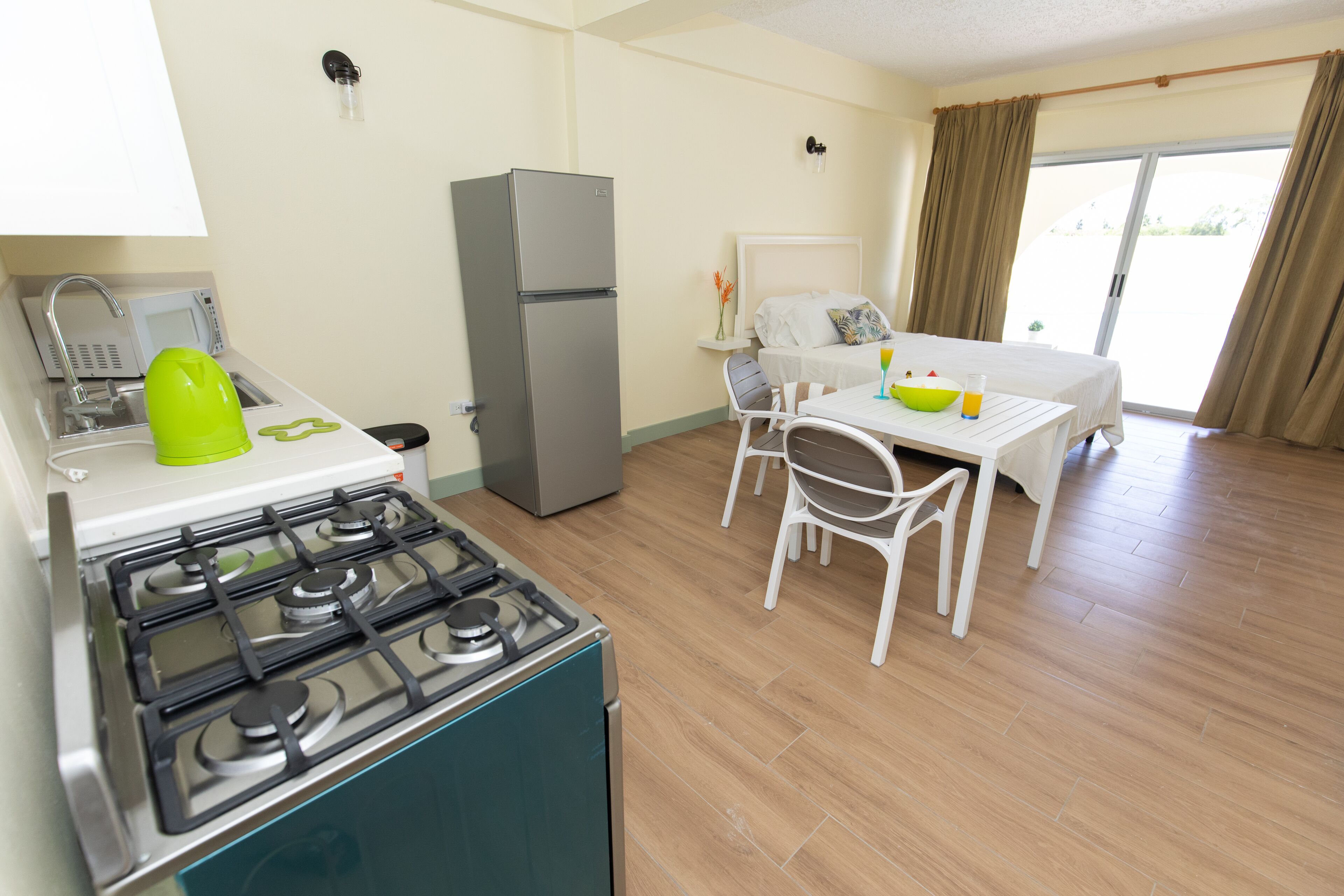 A compact kitchen with a stove, refrigerator, and a dining area with a table and chairs.
