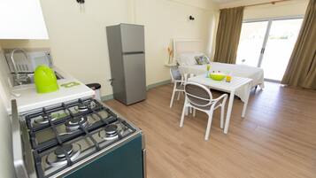 A compact kitchen with a stove, refrigerator, and a dining area with a table and chairs.