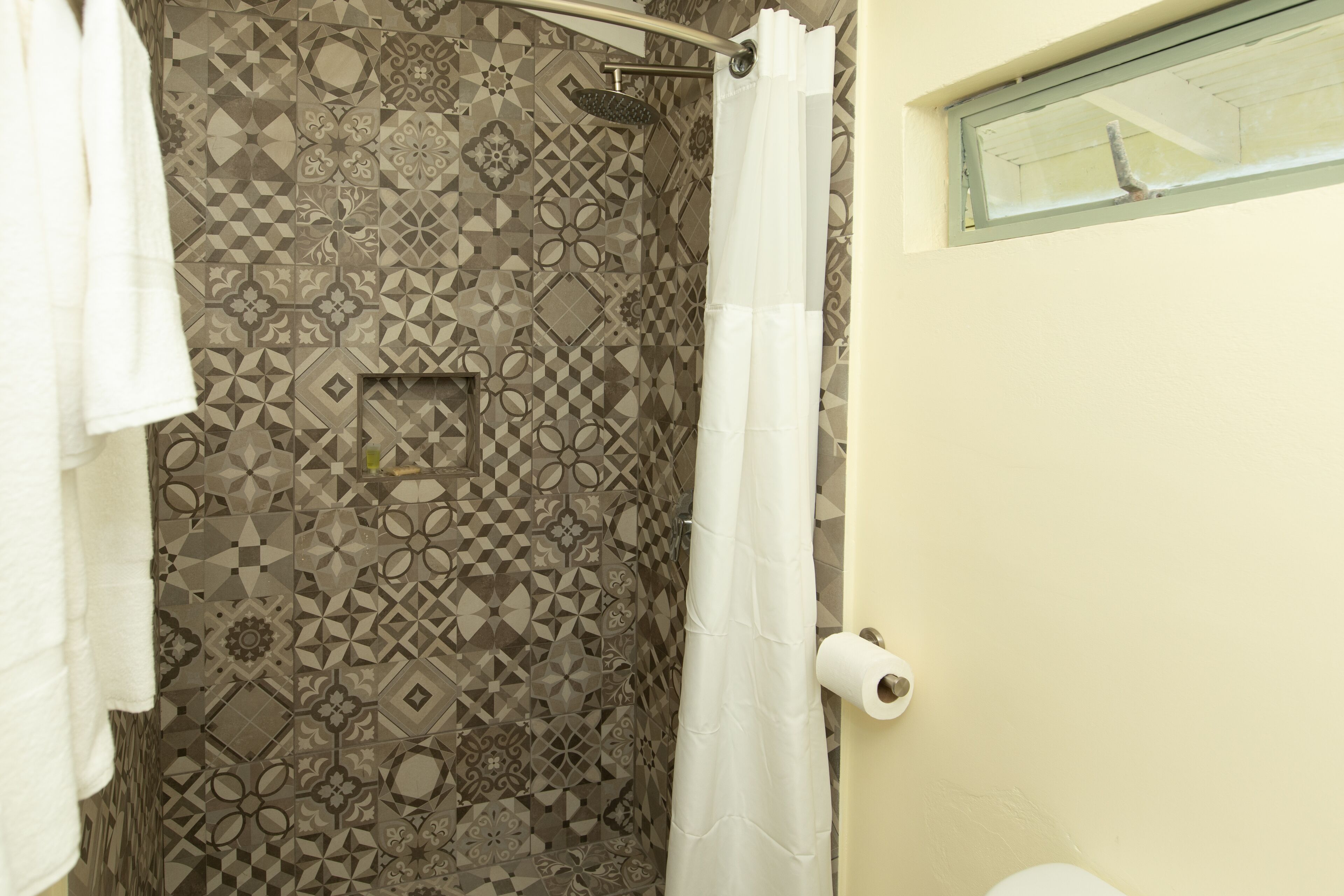 A bathroom with patterned tile walls, a shower curtain, and a toilet.