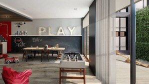 A modern kitchen with a foosball table, a dining area with a table and chairs, and a large wall with the word "PLAY" and a stop sign. - Urban 2BR Escape In-suite Laundry and Terrace (Laval)