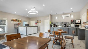 A modern hotel dining area with a central island, wooden tables, and chairs. - SureStay Plus Hotel by Best Western Ada (Ada)