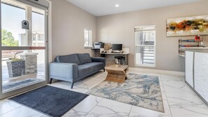 A modern living room with a grey sofa, a coffee table, and a large abstract painting on the wall. - SureStay Plus Hotel by Best Western Ada (Ada)