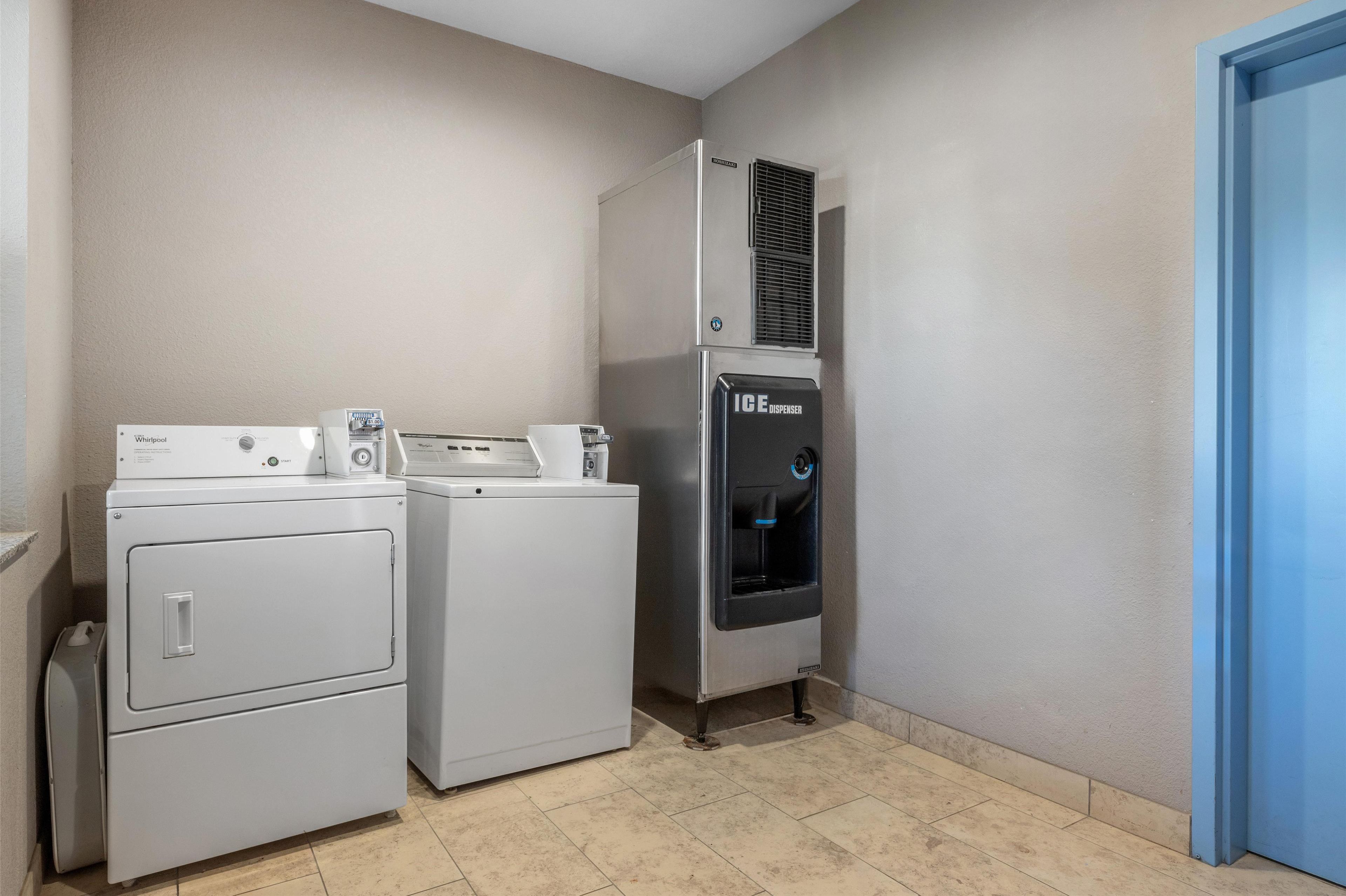 A laundry room with a Whirlpool washer, a dryer, and an ice dispenser refrigerator.