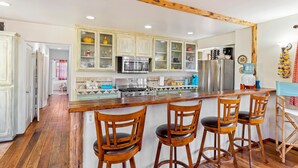 Une cuisine avec des tabourets de bar en bois, un îlot central et une poutre en bois au plafond.