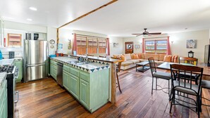 Une cuisine spacieuse dotée d’un îlot central, de planchers en bois et d’un coin repas avec une table et des chaises.