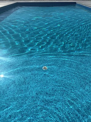 En klar pool med synliga vågor och ett avlopp i mitten.