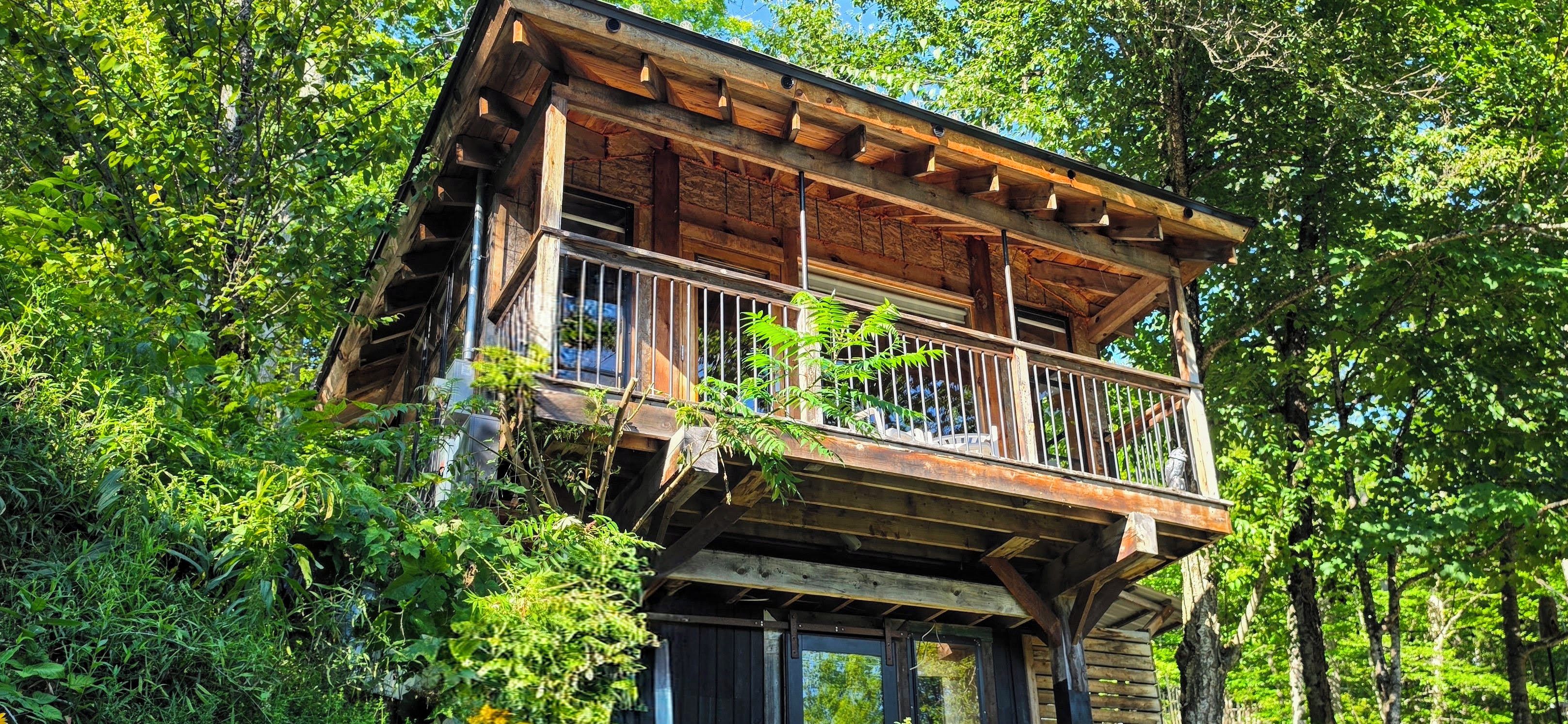 Eine Holzhütte mit Balkon, umgeben von dichtem Grün.